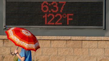 Una mujer pasa junto a un letrero que muestra la temperatura en Phoenix, Arizona.