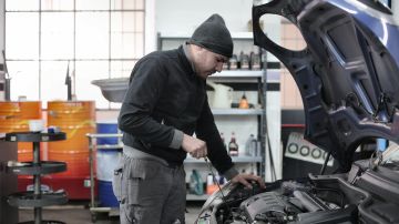Foto de un hombre revisando el aceite de motor de un auto
