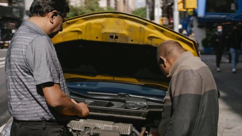 Foto de dos personas observando el motor de un auto