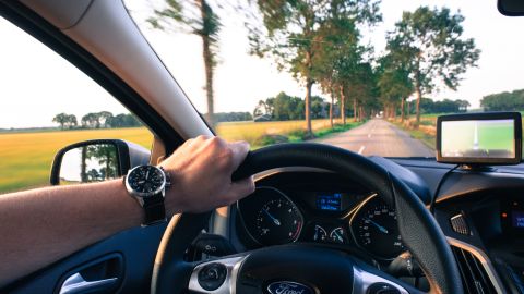 Foto del volante de un auto con la mano de la persona que lo conduce