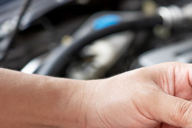 Foto de las manos de una persona con uno de los inyectores de un auto