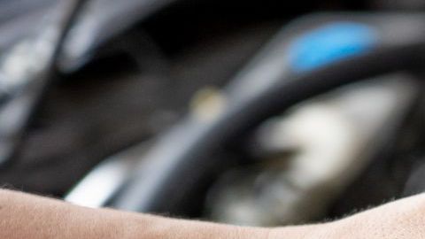 Foto de las manos de una persona con uno de los inyectores de un auto