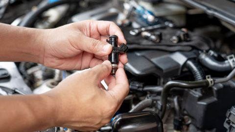 Foto de las manos de una persona con uno de los inyectores de un auto