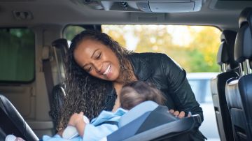 Foto de una mujer asegurando el asiento de su bebé en un auto