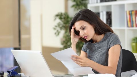 Foto de una mujer preocupada revisando un documento