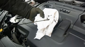 Foto de una persona revisando el aceite de motor de un auto