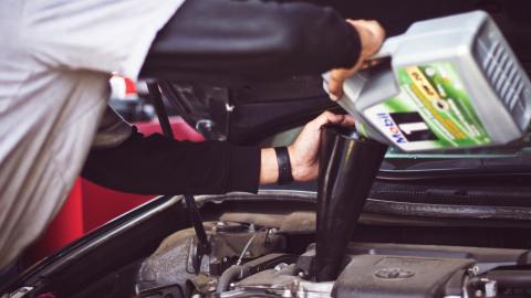 Foto de un hombre poniendo aceite en el motor en un taller mecánico