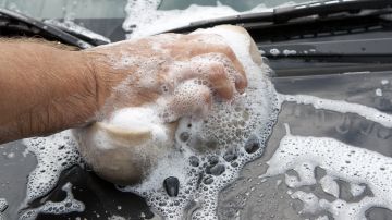Foto de la mano de una persona lavando un auto