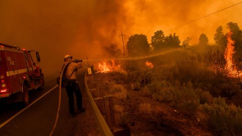 Bomberos intentan contener que el incendio Dixie cruce la autopista 395 en California.