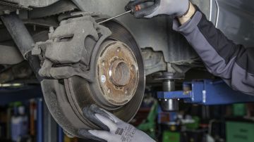 Foto de un auto en un taller mecánico mostrando el disco de freno