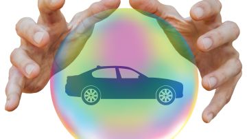 Foto de unas manos sobre una burbuja donde se puede ver un auto