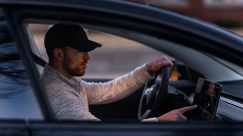 Foto de un hombre operando la pantalla de un auto de Tesla