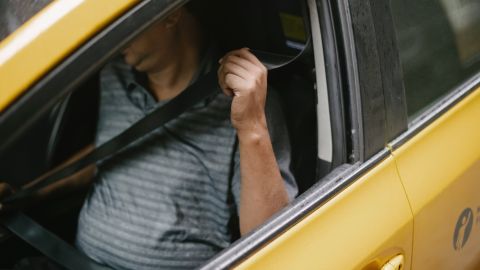 Foto del conductor de un auto asegurándose su cinturón de seguridad