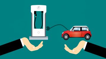 Imagen que muestra una mano con un cargador eléctrico para autos y otra con un auto eléctrico