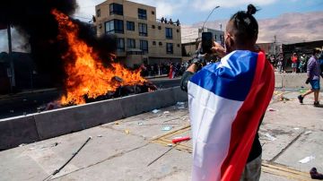 Un ciudadano toma una imagen de la quema de ropa y pertenencias de los migrantes que han llegado a Iquique en los últimos meses.