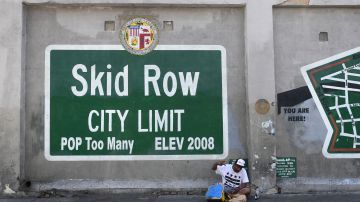 TOPSHOT - A man gestures while seated beside a Skid Row painting on a sidewalk in downtown Los Angeles on May 30, 2019. - The city of Los Angeles on May 29 agreed to allow homeless people on Skid Row to keep their property and not have it seized, providing the items are not bulky or hazardous. (Photo by Frederic J. BROWN / AFP) (Photo credit should read FREDERIC J. BROWN/AFP via Getty Images)