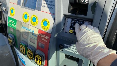 A woman wears a glove as a preventative measure against coronavirus, Covid-19, at a gas station in Los Angeles on March 18, 2020. - The US Senate passed a $100 billion emergency package on March 18 to help Americans hit hard financially by the coronavirus crisis, with more federal assistance in the pipeline. (Photo by Chris DELMAS / AFP) (Photo by CHRIS DELMAS/AFP via Getty Images)