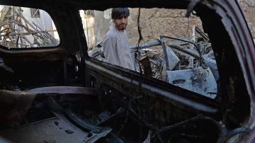 Un pariente de Ezmarai Ahmadi ante los restos del vehículo dañado en un ataque con aviones no tripulados de EE.UU.