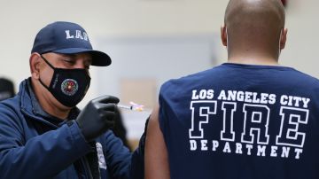 LOS ANGELES, CALIFORNIA - JANUARY 29: A Los Angeles Fire Department (LAFD) firefighter receives a Moderna COVID-19 vaccination dose from firefighter Michael Perez (L) at a fire station on January 29, 2021 in Los Angeles, California. LAFD has recorded a ‘sharp decline’ in coronavirus cases after firefighters began receiving the vaccine shots on December 28. (Photo by Mario Tama/Getty Images)
