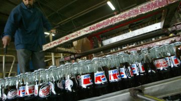 Pepsi bottles on a coveyor belt filled with a substitute based on a cola concentrate imported from Europe go past an employee of the Baghdad Soft Drinks Company at their plant in Baghdad's Zaafaraniya district 13 January 2004. The company held the Pepsi franchise in Iraq from 1984 to 1990 when sanctions were imposed on the country following the invasion of Kuwait. Pepsico last week officialized the agreement signed between them and the Baghdad Soft Drinks Company allowing them to resume production of Pepsi, Seven Up and Miranda, three very popular drinks in Iraq. The agreement grants the Baghdad Soft Drinks Company the license for central Iraq, around 40 percent of the market, and should create some 2,000 jobs, according to Hamid Jassem Khamis, the company's director general. "Real" Pepsi is expected to hit the streets within the next four months. AFP PHOTO/Mauricio LIMA (Photo credit should read MAURICIO LIMA/AFP via Getty Images)