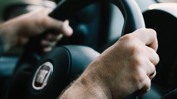 Foto de las manos de un hombre sobre el volante de un auto