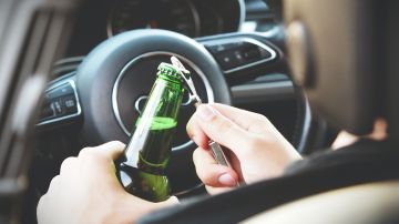 Foto de un conductores destapando una botella de licor