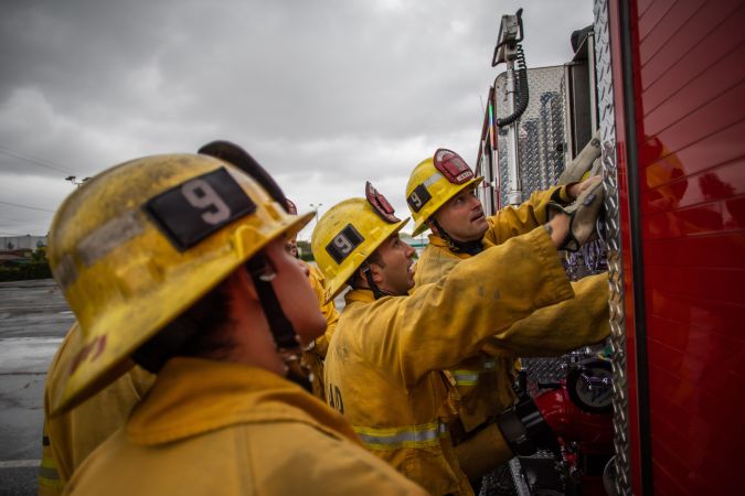Firefighters look up to fire truck instruments in a morning training session of the LAFD Station No9 team at Skid Row on April 12, 2020 in downtown Los Angeles, California. - One of the busiest fire station in the country , LA Fire Station 9 is on the front lines of California's homeless crisis e Coronavirus pandemic. (Photo by Apu GOMES / AFP) (Photo by APU GOMES/AFP via Getty Images)