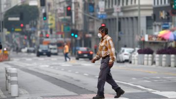 A man wearing a face mask walks across a street in downtown Los Angeles, California, on April 30, 2020, amid the novel coronavirus pandemic. - A recent surge in the number of novel coronavirus cases and deaths linked to COVID-19 has brought California to two milestones, as the state is poised to surpass 50,000 infections and 2,000 deaths. (Photo by Robyn Beck / AFP) (Photo by ROBYN BECK/AFP via Getty Images)