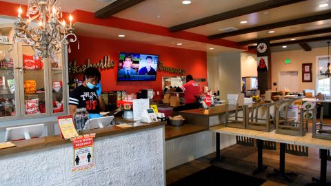 An employee takes a phone order as another packs up a takeout order while the indoor seating area remains closed at the Hotville Chicken restaurant at Baldwin Hills Crenshaw in Los Angeles, California, November 24, 2020. - It's been a rough year for Black-owned small businesses, and the latest surge in coronavirus cases suggests a festive season without much celebration. "Black Friday" normally kicks off the holiday shopping season the morning after Thanksgiving. But rising coronavirus cases have prompted fresh restrictions in Los Angeles and elsewhere. The new rules mean Hotville Chicken, a south Los Angeles restaurant specialzing in "Nashville-style" spicy dishes, will have to shut its outdoor eating space after already closing the dining room. (Photo by Patrick T. Fallon / AFP) / TO GO WITH AFP STORY BY JOHN BIERS "Covid-19 dampens holiday cheer for Black small businesses" (Photo by PATRICK T. FALLON/AFP via Getty Images)