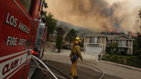 TOPSHOT - A firefighter control monitors a fire burning behind houses in the suburb of Glendale on the outskirts of Los Angeles city on September 1, 2009. A deadly wildfire roared out of control above Los Angeles, leaving two firefighters dead, forcing thousands to flee and threatening a crucial telecommunications facility. The monster blaze raging in mountains north of the densely populated metropolis had ripped through more than 105,000 acres (43,000 hectares) of tinder-dry forest and was "spreading in every direction," authorities said. An army of more than 2,500 firefighters was battling the blaze in the Angeles National Forest which remained only five percent contained and sent a giant white mushroom cloud of smoke across the city. AFP PHOTO/Mark RALSTON (Photo by MARK RALSTON / AFP) (Photo by MARK RALSTON/AFP via Getty Images)