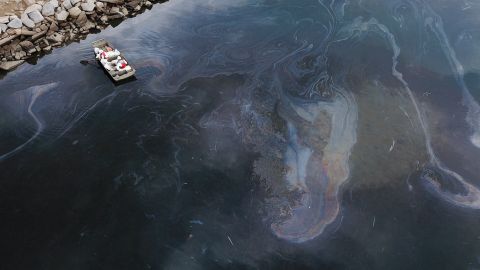 TOPSHOT - This aerial picture taken on October 4, 2021 shows environmental response crews cleaning up oil that flowed near the Talbert marsh and Santa Ana River mouth, creating a sheen on the water after an oil spill in the Pacific Ocean in Huntington Beach, California. (Photo by Patrick T. FALLON / AFP) (Photo by PATRICK T. FALLON/AFP via Getty Images)