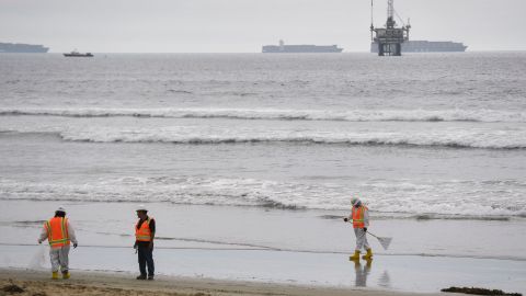 An oil platform and cargo container ships are seen on the horizon as environmental response crews clean the beach after an oil spill in the Pacific Ocean in Huntington Beach, California on October 4, 2021. (Photo by Patrick T. FALLON / AFP) (Photo by PATRICK T. FALLON/AFP via Getty Images)