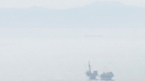 An oil platform (L) and cargo container ship (R) offshore along the coastline are seen from a US Coast Guard HC-27J Spartan aircraft during a media flight after an oil spill in the Pacific Ocean in Orange County, California on October 6, 2021. - The US Coast Guard is investigating a possible anchor strike as the cause of a broken pipeline that has spewed tens of thousands of gallons of crude oil into the sea off California, media reported on October 5. (Photo by Patrick T. FALLON / AFP) (Photo by PATRICK T. FALLON/AFP via Getty Images)