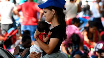 Mujeres migrantes cargan a sus hijos durante su caminar rumbo a la Ciudad de México.