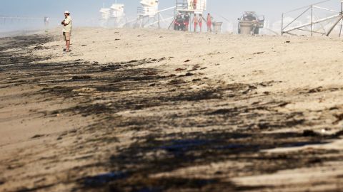 HUNTINGTON BEACH, CALIFORNIA - OCTOBER 03: A person stands near oil washed up on Huntington State Beach after a 126,000-gallon oil spill from an offshore oil platform on October 3, 2021 in Huntington Beach, California. The spill forced the closure of the popular Great Pacific Airshow with authorities urging people to avoid beaches in the vicinity. (Photo by Mario Tama/Getty Images)