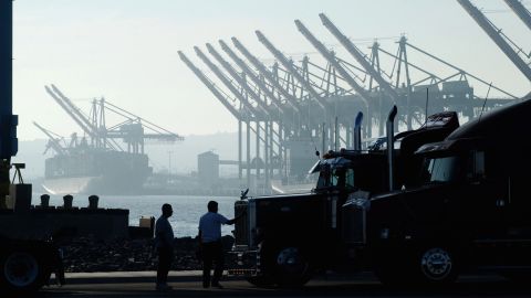 LOS ANGELES, CA - OCTOBER 9: A trucker polishes his rig while waiting near ships and cranes for the re-opening of the Port of Los Angeles on October 9, 2002 in Los Angeles, California. President George W. Bush used a court order to force the opening of West Coast ports tonight, ending an estimated $1 billion-per-day loss to the United States economy. (Photo by David McNew/Getty Images)