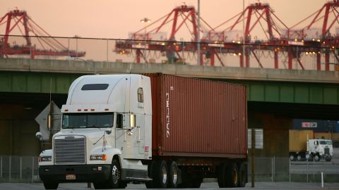 LONG BEACH, CA - JULY 06: Trucks carry shipping containers near a dock where cranes can be seen in the distance at the ports of Long Beach and Los Angeles on July 6, 2006 in Long Beach, California. In the Los Angeles area, studies indicate that diesel exhaust from trucks, locomotives, heavy equipment and ships causes cancer and is responsible for 70% of pollution-related health problems and hundreds of deaths every year. Rather than wait for the international agency that regulates the global shipping industry, the International Maritime Organization, to implement considered changes to strengthen emissions standards for cargo vessels, the ports recently unveiled an ambitious clean-air plan that could significantly improve air quality. The proposal seeks to reduce diesel emissions from cargo ships, trains and trucks by more than 50% over a five-year period at a cost of $2-billion.Almost 5,800 ships called at the ports of Los Angeles and Long Beach in 2005 released about 14,000 tons of air pollutants. Many ships emit as much exhaust per day as 12,000 cars. (Photo by David McNew/Getty Images)