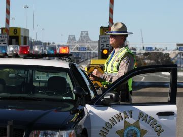 OAKLAND, CA - OCTOBER 28: California Highway Patrol officer Rick Baller stands next to his car as he guards the closed toll plaza leading to the San Francisco Bay Bridge October 28, 2009 in Oakland, California. The San Francisco Bay Bridge was abruptly closed Tuesday evening after two steel tie rods and a crossbeam from a steel saddle broke and fell onto the upper deck of the bridge landing on three vehicles and causing one person to suffer injuries. The eastern span of the bridge is undergoing seismic renovation and is expect to be completed in 2013. (Photo by Justin Sullivan/Getty Images)