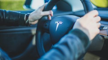 Foto de una persona con las manos puestas sobre el volante de un auto Tesla