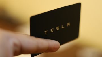 Foto de la mano de una persona con una tarjeta de Tesla