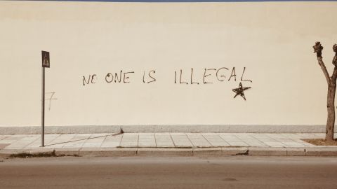 Foto de una pared con la frase "no one is illegal"