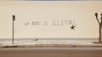 Foto de una pared con la frase "no one is illegal"