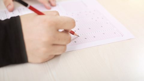 Foto de las manos de una persona presentando un examen escrito