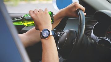 Foto de una persona consumiendo alcohol mientras conduce