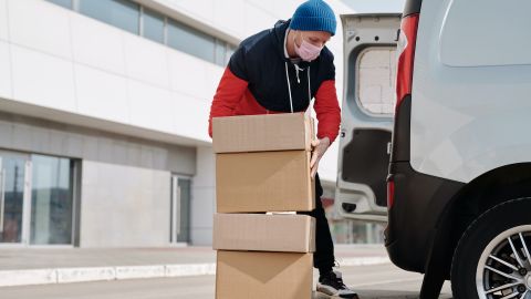 Foto de un repartidor subiendo algunas cajas al vehículo de carga