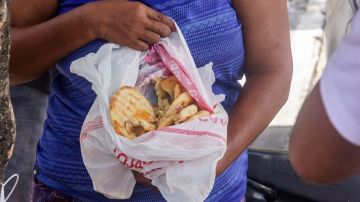 El desperdicio de unos es comida para otros. Una mujer muestra unos panes recién encontrados en un camión de basura.