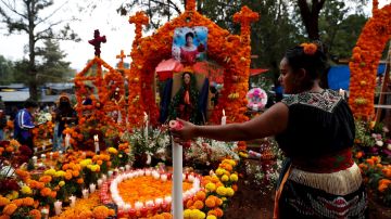 Familias en México adornan tumbas de sus seres queridos en el Día de Muertos.