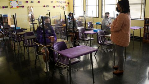 A teacher speaks with students as they return to in-person learning at St. Anthony Catholic High School during the Covid-19 pandemic on March 24, 2021 in Long Beach, California. - The school of 445 students implemented a hybrid learning model, with approximately 60 percent of students returning to in an in-person classroom learning environment with Covid-19 safety measures including face masks, social distancing, plexiglass barriers around desks, outdoor spaces, and schedule changes. (Photo by Patrick T. FALLON / AFP) (Photo by PATRICK T. FALLON/AFP via Getty Images)