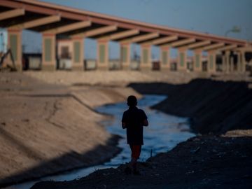 Un niño camina a lo largo del Río Bravo, donde muchos han perdido la vida.