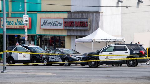 A black vehicle covered with stickers is cornered by police cars at the corner of Fairfax Avenue and Sunset Boulevard where a body covered in a white sheet lies next to it in Los Angeles on April 24, 2021 in what appears to be an officer-involved shooting. - On the evening of the shooting the LAPD official twitter account read: There has been an Officer-Involved Shooting on Sunset Blvd. near Fairfax in Hollywood Division. Around 2:35 p.m. officers were heading to a radio call with their lights and sirens on when a car pulled in front of them, stopped suddenly and reversed into the police car. The driver of the car exited, was wearing body armor, and had his right hand concealed behind him. He moved toward the officers who had exited their patrol car. He counted "3, 2, 1" and began to move his arm to the front of his body, at which time there was an officer involved shooting. The man was struck by gunfire and pronounced deceased at scene. Force Investigation Division detectives are on scene conducting interviews and gathering evidence.The man who was shot and killed by the Los Angeles Police Department has been identified as 34-year-old Richard Solitro. (Photo by VALERIE MACON / AFP) (Photo by VALERIE MACON/AFP via Getty Images)